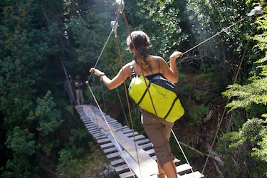 a woman crossing a perilous rope-bridge